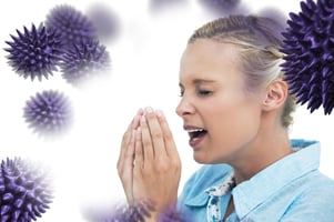 Blonde woman sneezing with hands in front of her face against virus