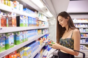 Woman reading food label under bright led grocery store lighting